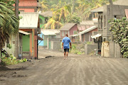 A man walks down a street after a series of eruptions from La Soufriere volcano covered the area with a thick layer of ash in Georgetown, Saint Vincent and the Grenadines, on April 13 2021.  