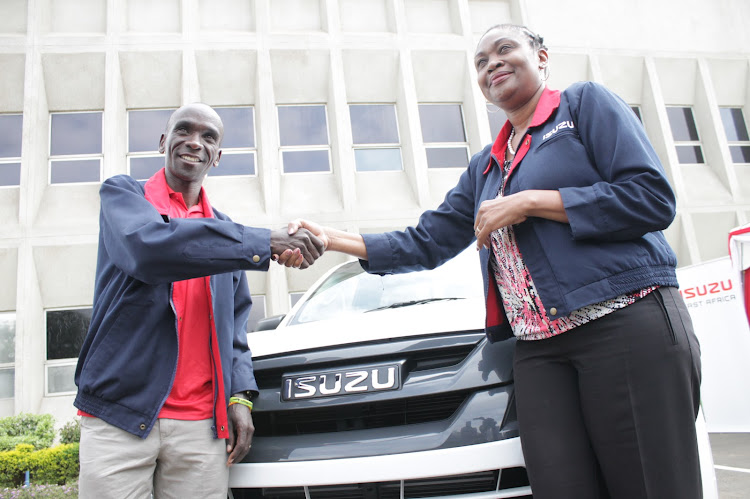 World marathon record holder Eliud Kipchoge shakes hands with Isuzu East Africa MD Rita Kavashe in front of the single cab offered to him if he breaks the 2-hour mark.