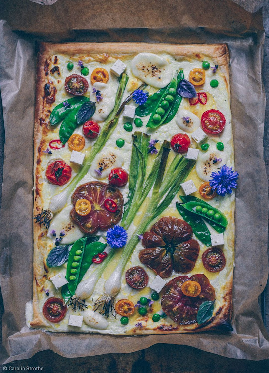 "Celebrating summer with this spectacular veg tart – topped with buffalo mozzarella, feta, heirloom tomatoes, pea pods, spring onions and corn flowers."