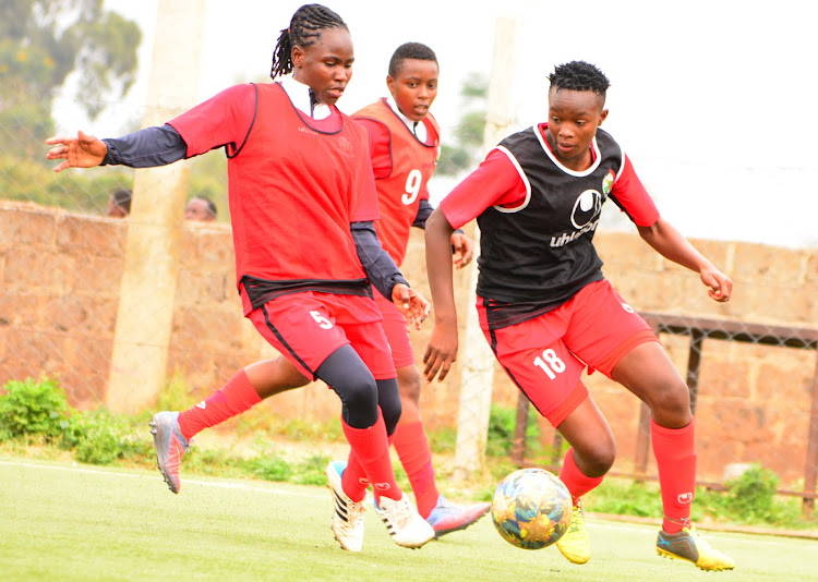 Harambee Starlets' Cynthia Shilwatso (R) charges past Dorcas Shikobe and Wincate Kaari during a training session at Camp Toyoyo.