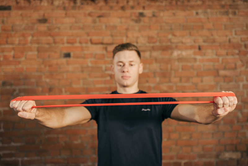 https://www.pexels.com/photo/man-in-black-crew-neck-t-shirt-stretching-a-resistance-band-6339596/