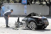 A police officer inspects the remains of Areff Haffejee's Audi R8 V10 Spyder six-speed sports car. File photo.