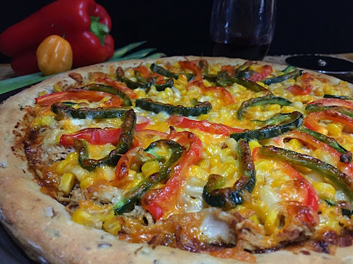 A colorful chicken pizza with strips of bell peppers and topped with cheese