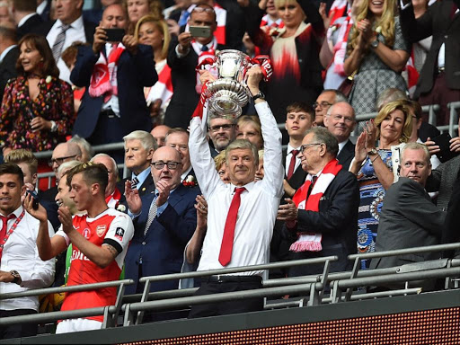 Arsene Wenger smiles as he lifts the FA Cup above his head; he has now won seven FA Cup trophies./DAILY MAIL