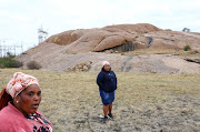 Zameka Nungu and Nosihle Ngweyi, two widows who lost their husbands during the brutal killing of miners, speak about how life has not changed for the better, in front of the hill where police killed 34 miners in 2012 in the 