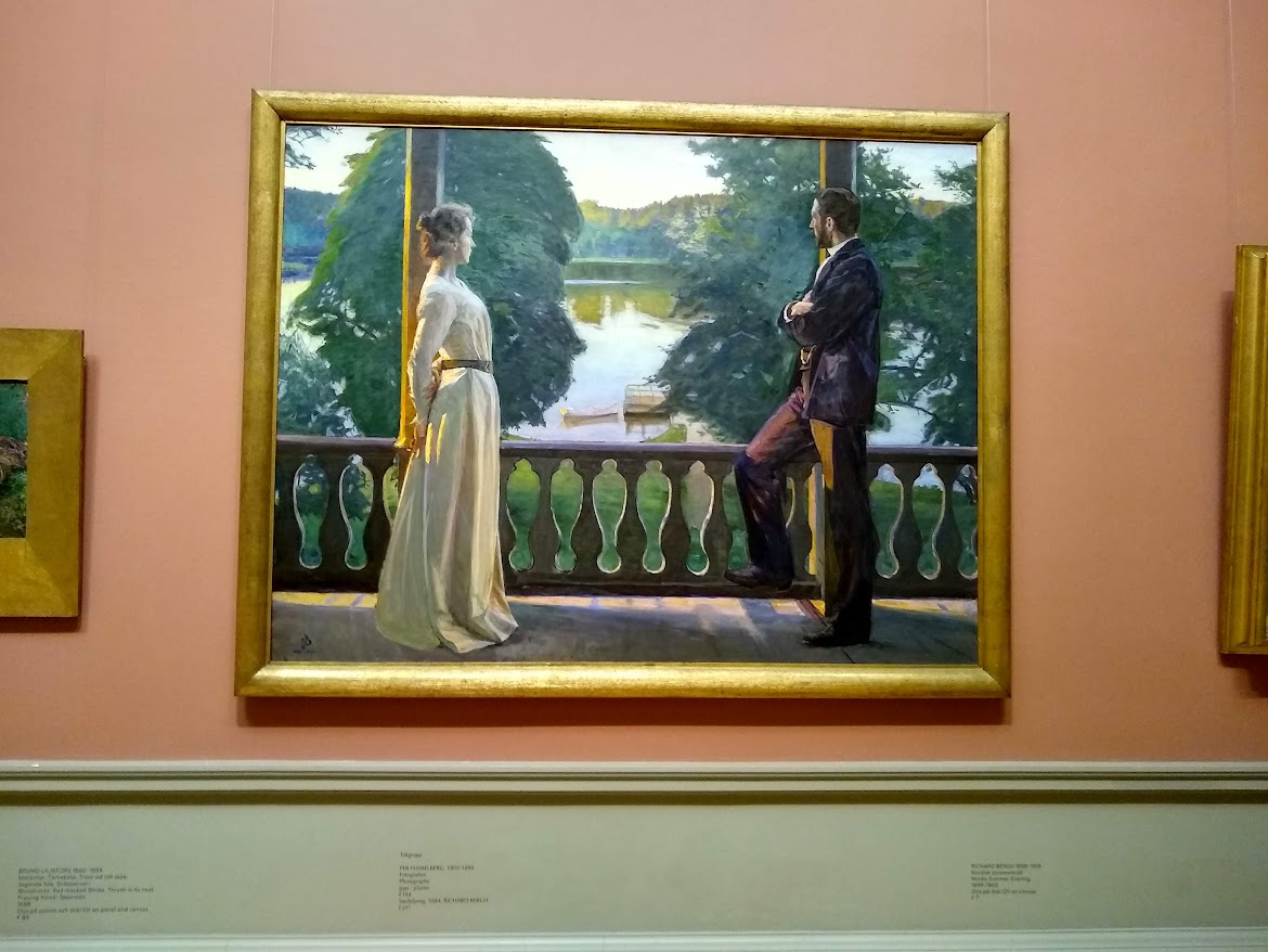 Photo d'une peinture. Une femme en robe blanche et un homme en costume sombre tourne le dos au spectateur et regarde un lac entouré d'arbres