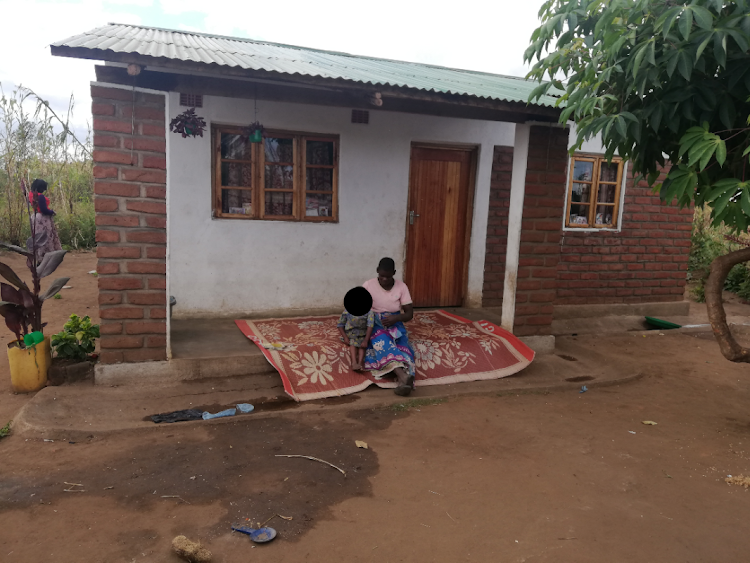 Cecilia Lapani, from Likhomo Village in Chiradzulu district, south of Malawi, sitting in front of her new home with her daughter Lydia. Having social support has helped this mother of seven, who is HIV-positive, to better adhere to treatment.