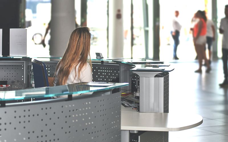 Een vrouw achter de receptie bij een bedrijf, om een freelance invaller administratie weer te geven