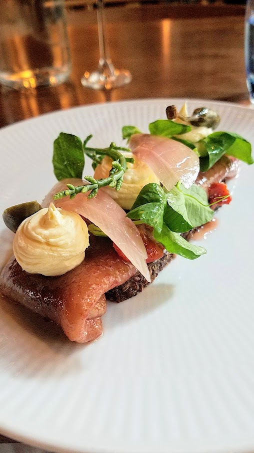 Restaurant Palaegade in Copenhagen offering traditional Danish smørrebrød of Red pickled herring with rosehips, creme fraiche, and pickled onion