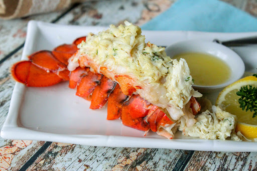 Crab stuffed lobster tail on a plate with butter for dipping.