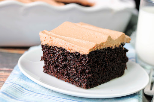 A slice of Black Magic Cake with chocolate frosting on a plate.