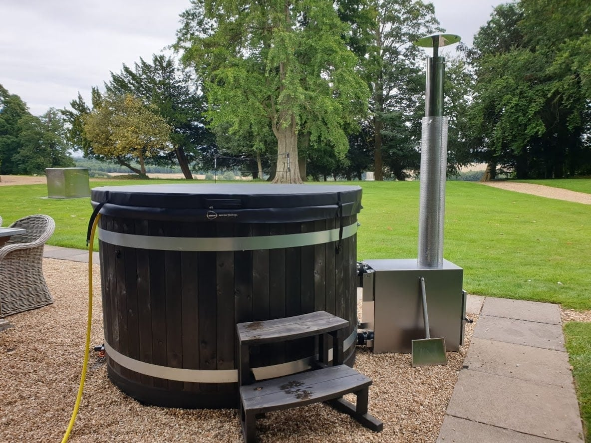 A wood-fired hot tub from Kirami on a gravel base.