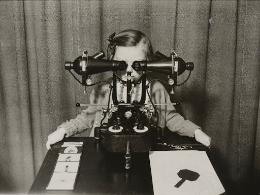 A young girl sitting at a synoptoscope in the Orthoptics Department, King Edward VII Memorial Children's Hospital, Ladywood, Birmingham