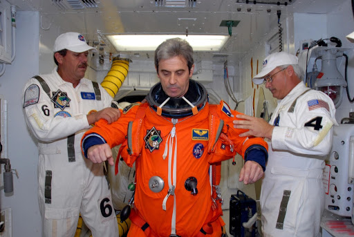 Suit technicians help space shuttle Atlantis STS-122 Mission Specialist Leopold Eyharts with his flight and entry suit.