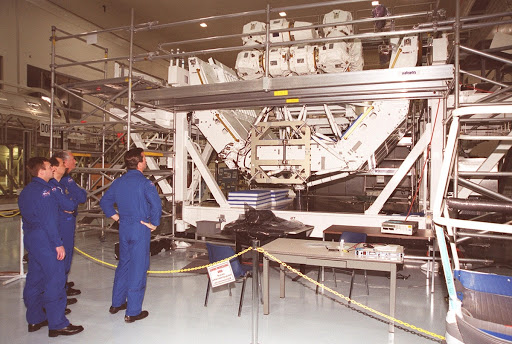 Members of the STS-100 crew look which is on a workstand in the Space Station Processing Facility.
