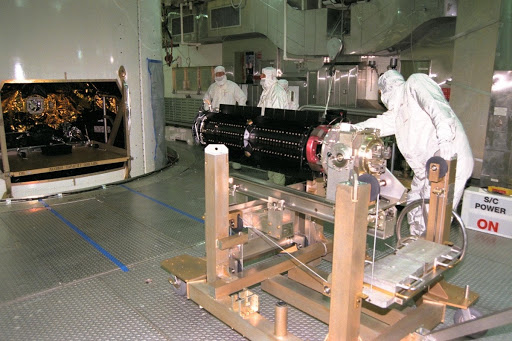 At Launch Complex 40 workers are installing three Radioisotope Thermoelectric Generators RTGs on the Cassini spacecraft.
