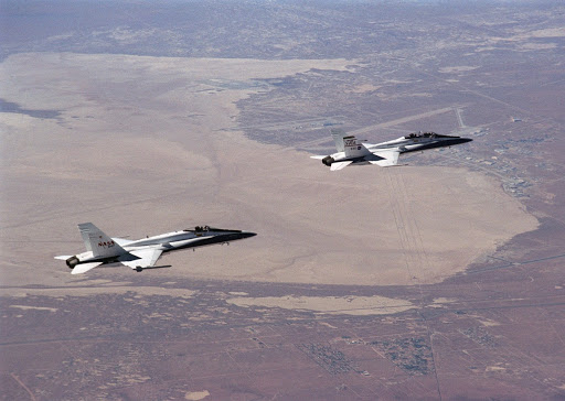 Two F A-18s from the NASA Dryden Flight Research Center gain altitude near Rogers Dry Lake.