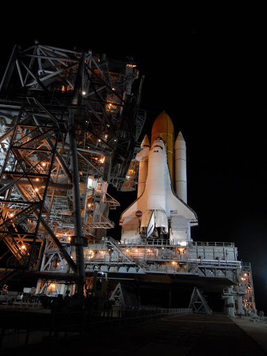 Bathed space shuttle Discovery is revealed after the rotating service structure has been rolled back.