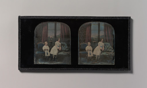 [Stereograph, Two Children Standing Between Furniture in a Studio Parlor Setting]