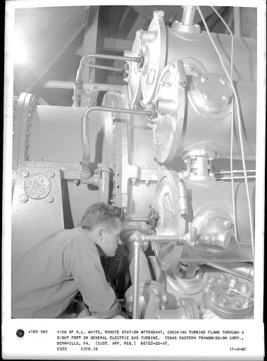 View of R.L. White, remote station attendant, checking turbine flame through a sight port on General Electric gas turbine. Texas Eastern Transmission Corp., Bernville, PA.