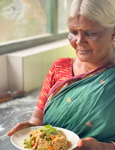 Janagiamma, leader from the indigenous Kurumba community of the Nilgiris holding her millet chicken biryani