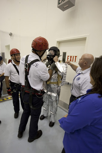 Fire and rescue personnel participate in an exercise known as crew egress evaluation from an Orion mock-up.