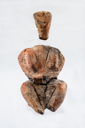 Small female headless statuette including head with tilted triangular face