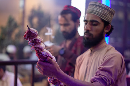 Man aligns the meat on skewer in Peshawar