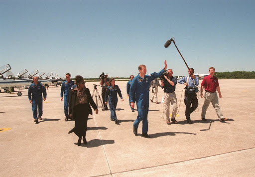James Halsell waves to the media as he and crew members cross the tarmac to a waiting bus.