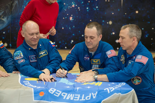 AirshowIn the Korolev Museum sign a flag bearing their Soyuz MS-08 crew patch insignia during a tour of the museum.