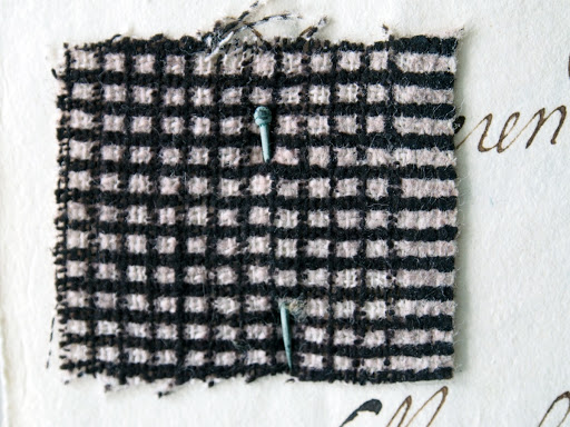 Textile sample pinned onto a letter