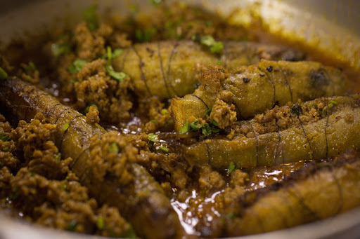 Parboiled bitter gourds are added to a pan with spices and yogurt and cooked down