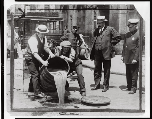 Pouring Out Beer During Prohibition as Law Enforcement Looks On