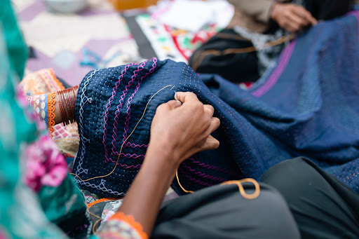 A second shot of a woman sewing a quilt in Sukkur