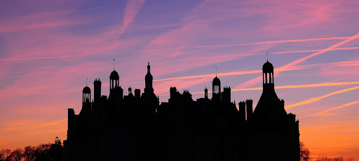 La silhouette du château se dessine dans le ciel au crépuscule