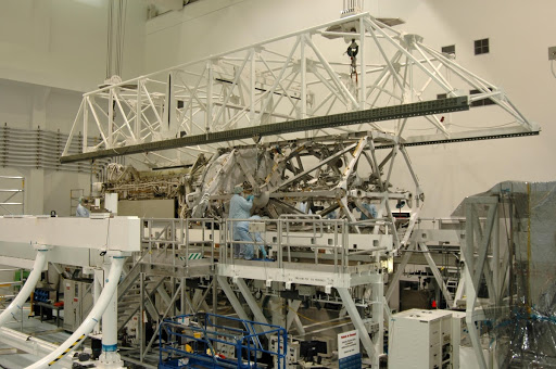 An overhead crane lowers the S3 S4 integrated truss structure onto a work stand.