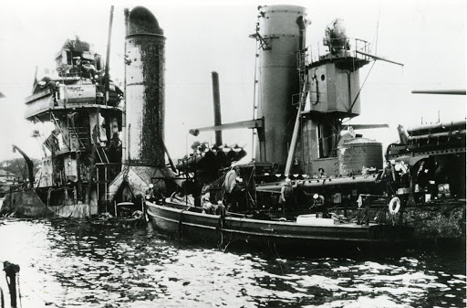 Wreckage of USS Shaw in YFD-2. Motor launch alongside appears to be from USS Dobbins AD-3 a destroyer tender. Launches of this type came in 50ft and lesser lengths and were nested.