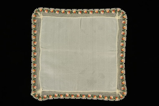 White silk handkerchief bordered with lace and pink flowers brought to the US by a Jewish family fleeing German occupied Poland