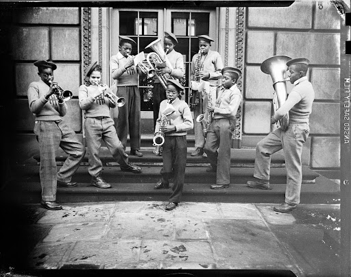 Boys wearing sweaters monogrammed "H. H.," playing brass instruments on steps inside courtyard of Pittsburgh Board of Education building, Oakland