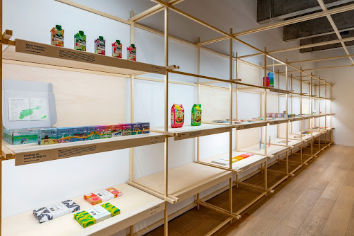 Photograph of a few of the packages on display, such as ‘Nissin Traveling Ethnic,’ ‘History of Wajima Rice from the Nōtō Peninsula,’ and ‘Yasai Seikatsu 100 Smoothie.’