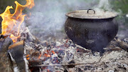 Cooking traditional soup over an open fire in the forest. Bonfire picnic in the forest. A pot of soup cooked over a fire.