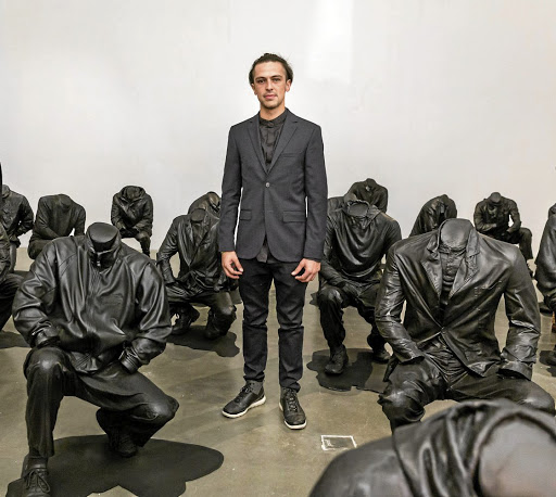 Haroon Gunn-Salie stands amid figures of headless mineworkers; the piece entitled 'Senzenina' is currently on show in London.