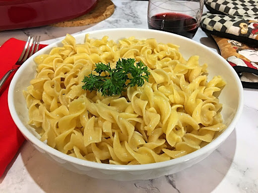 A bowl of nicely cooked Buttered Egg Noodles garnished with parsley.