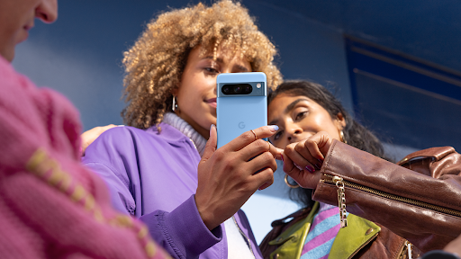 Un grupo de personas interactúa con un Pixel 8 Pro azul.