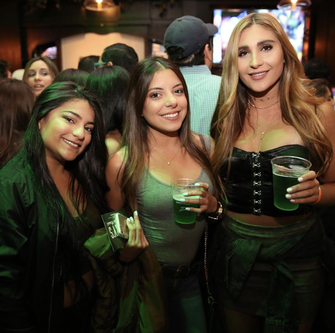 women in a bar celebrating st. patrick's day by drinking green beer