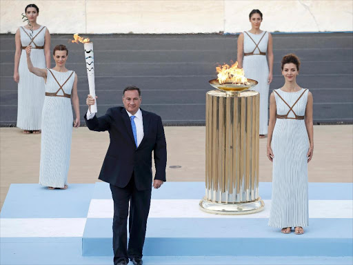 Spyros Capralos, head of the Hellenic Olympic Committee (C), holds an Olympic torch besides Greek actress Katerina Lehou (R), playing the role of High Priestess, during the handover ceremony of the Olympic Flame to the delegation of the 2016 Rio Olympics, at the Panathenaic Stadium in Athens, Greece, April 27, 2016. REUTERS/Alkis Konstantinidis