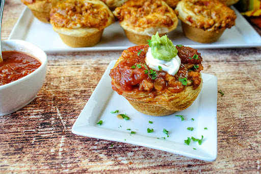 Taco Cups topped with sour cream, salsa, and guacamole.