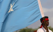 A protester carries the Somali national flag during a demonstration against Al-Shabaab militant group after last weekend's explosion in KM4 street in the Hodan district at the stadium Koonis in Mogadishu, Somalia on October 18 2017. 
