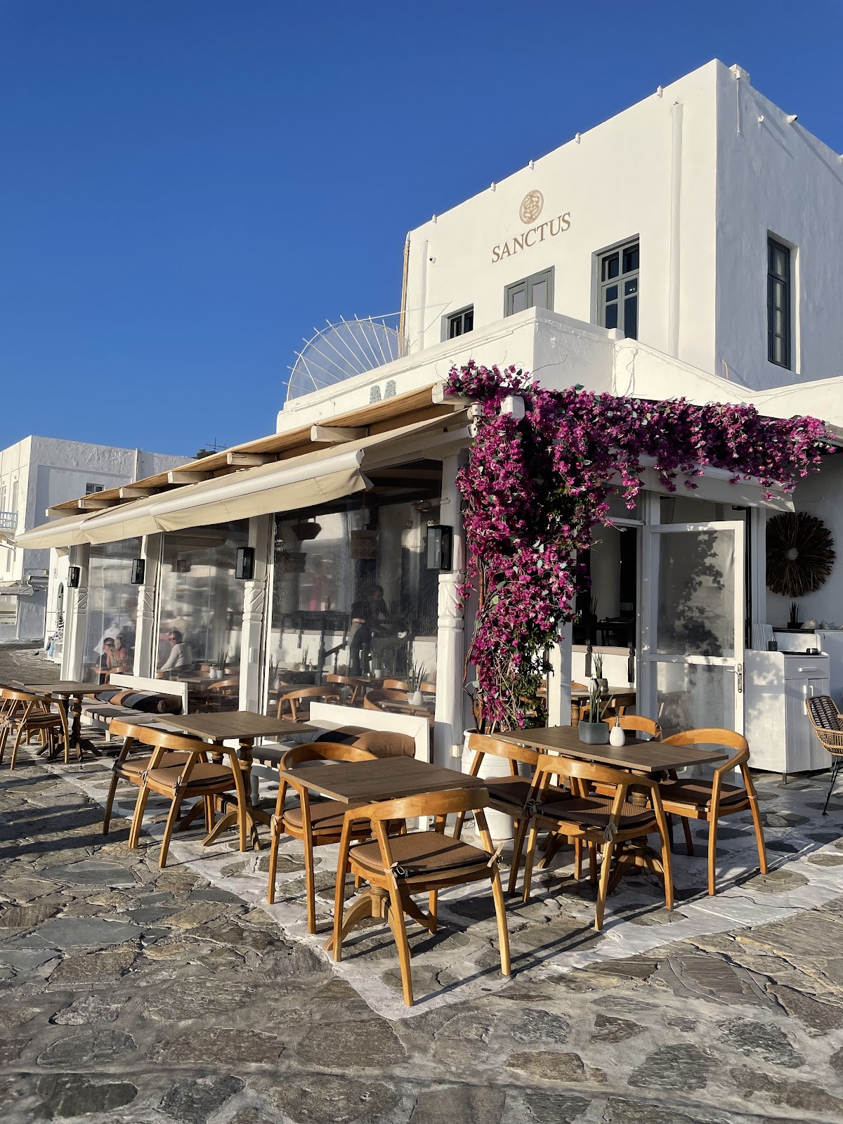 Restaurant typique grec avec façade blanche et fleurs pendantes