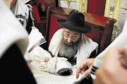 A rabbi holds his eight-day-old grandson during a circumcision ceremony in Brussels, Belgium Picture: FRANCOIS LENOIR/REUTERS